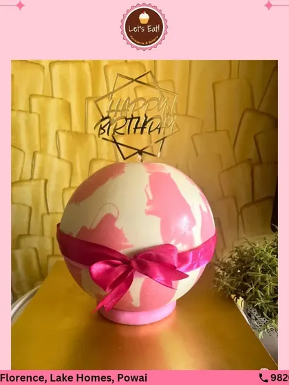 A surprise-inside piñata cake. This chocolate sphere, decorated with a pink ribbon, is designed to be broken open to reveal a hidden stash of treats, adding an element of fun to the celebration.