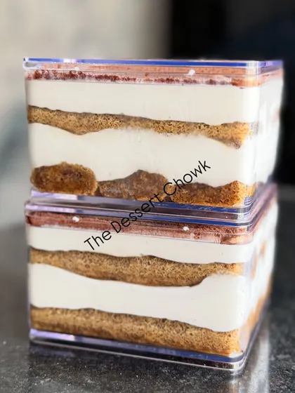 A side view of my Tiramisu tubs, stacked to show the neat, delicious layers of cream and coffee-soaked biscuits.