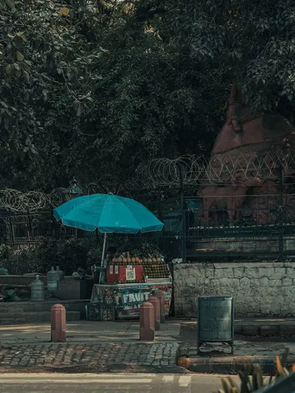 A fruit cart with a bright blue umbrella, adding a splash of color to the scene. Sometimes, a single colorful object can be the hero of a street photograph.