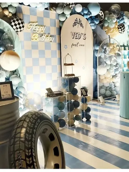 For Ved's "fast one," we went all out with a race car theme. This setup features custom backdrops with checkered flags, a striped floor for the "racetrack," and even a real tire prop to make the birthday boy feel like he's at the Grand Prix.