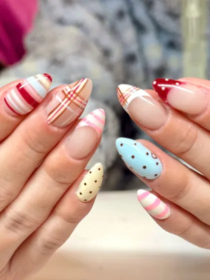 Soft shades and sweet details give these nails major Valentine energy. This mismatched set features stripes, plaid, and polka dots in a romantic color palette of red, pink, blue, and cream.