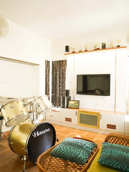 A unique living room with a drum set as a centerpiece, showcasing how we design spaces that reflect our clients' passions. The TV unit is simple and functional, allowing personal items to shine.