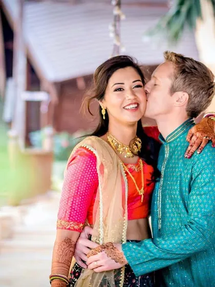 A sweet kiss on the cheek. This photo captures a candid, loving moment between a multicultural couple during their pre-wedding festivities.
