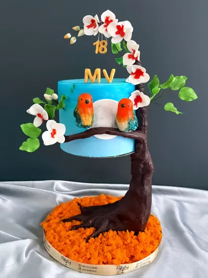 A full view of the gravity-defying lovebird cake, showcasing the sculpted tree trunk that supports the entire cake.