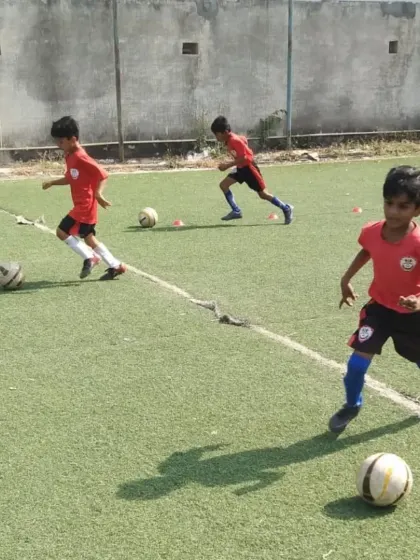 Three young players practicing their dribbling skills in unison during a grassroots session.