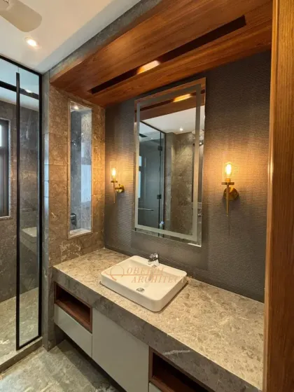 A close-up of the vanity area, with warm sconce lighting that complements the natural tones of the wood and stone.