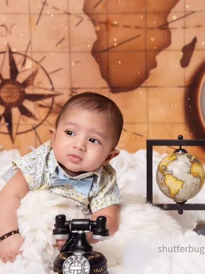 A curious baby enjoying tummy time, reaching for a vintage telephone in our world traveler theme.