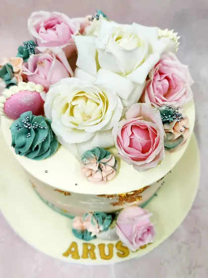 We create a botanical wonderland with this buttercream floral cake. A beautiful bouquet of fresh white and pink roses is artfully arranged with piped succulents in shades of teal and pink, accented with gold leaf for a touch of modern glamour.