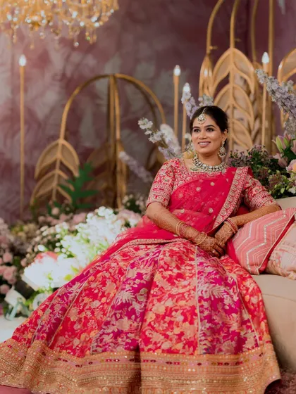 My gorgeous bride's reception look. She is seated amidst beautiful floral decor, and her vibrant pink lehenga is complemented by a soft, glowing makeup look.