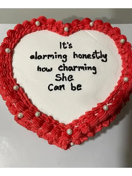A top-down view of the vintage heart-shaped cake, showing the intricate piping border and the custom message.