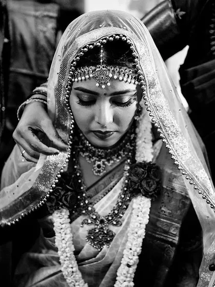 A beautifully composed black and white portrait of a bride in a moment of quiet reflection. The veil and her serene posture give this image a classic, reverent quality.
