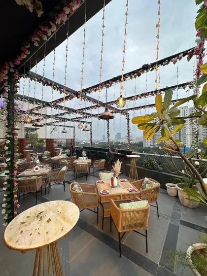 The beautifully decorated rooftop seating area for the restaurant launch, with hanging floral vines creating a garden-like feel.