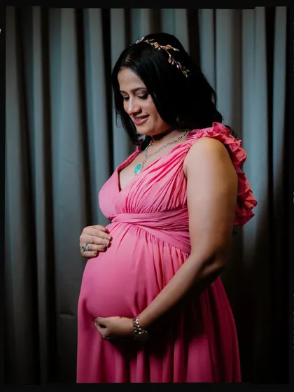 A classic and elegant solo maternity portrait. The mother-to-be is captured in a three-quarter pose, cradling her bump, with a simple background that keeps all the focus on her radiant glow.