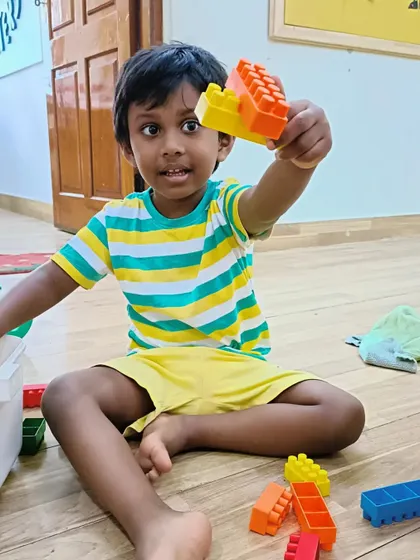 A new student exploring building blocks on his first day. Play is the first step to learning and making friends.
