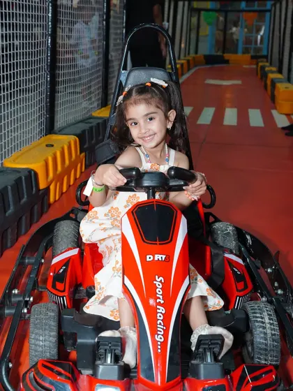 This little girl looks ready to win, sitting confidently in her red go-kart on our clearly marked indoor track.
