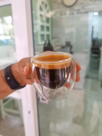A perfectly pulled espresso shot, held up to the light. You can see the rich color and the thick, stable crema, a sign of a well extracted and high quality coffee.