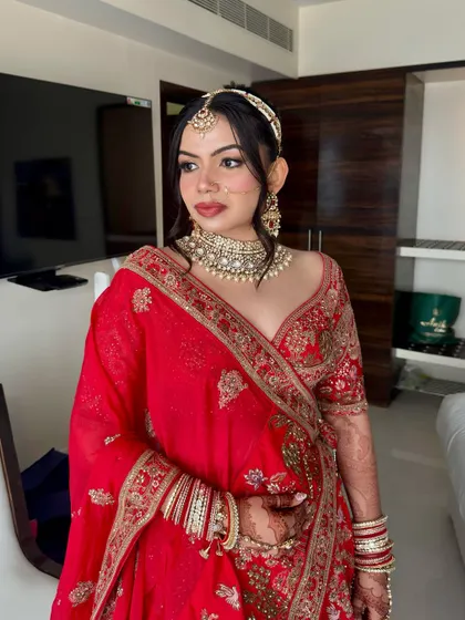 A full view of this detailed bridal look, showcasing the elegant red lehenga and sophisticated makeup.