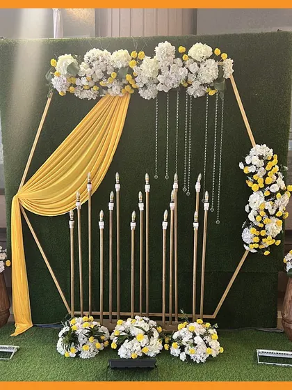 A modern and stylish photo corner for a Mehendi event. The hexagonal frame, candle display, and yellow draping create a chic backdrop for guest photos.