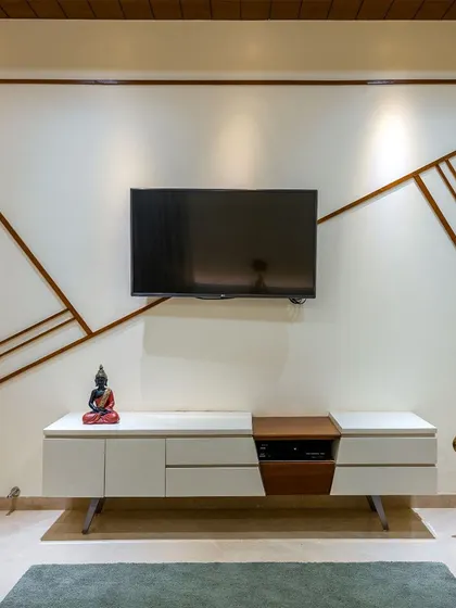 In this living room, thin wooden strips are inlaid into the wall in an abstract pattern, creating a unique and subtle feature that contrasts with the smooth white surface.