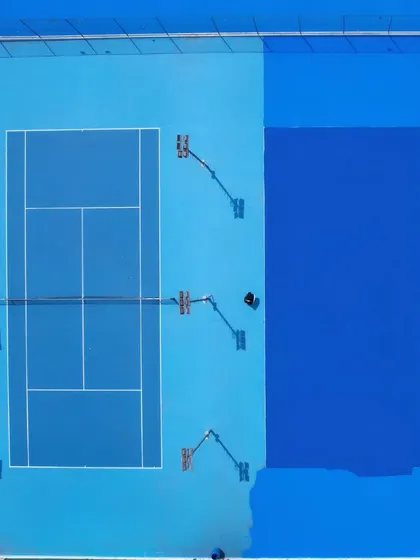 An overhead shot captures the meticulous process of applying a fresh coat to our courts. This dedication to maintenance ensures our players always train on surfaces that meet the highest standards.