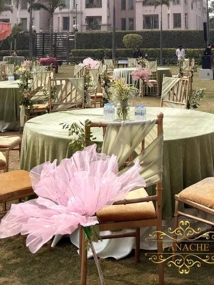 A close-up of the chair decor, featuring a large, whimsical organza flower in a soft pink hue.