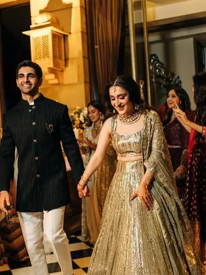A candid moment of a couple entering their event. I love seeing the final look come together, with her shimmering gold lehenga and his classic black bandhgala.