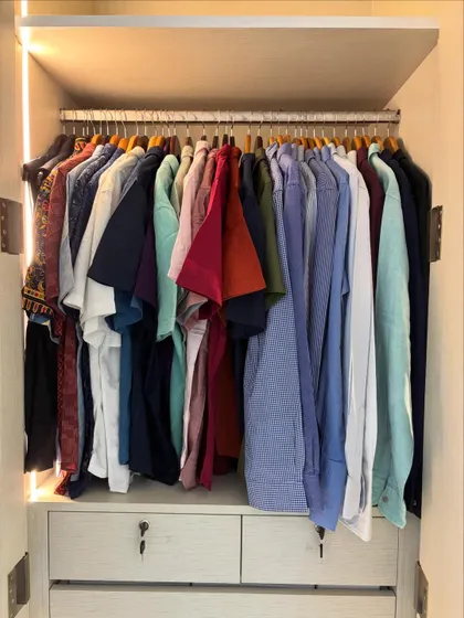This is a great example of a simple, effective system for a men's wardrobe. By organizing shirts by color and type, getting ready becomes a quick and stress-free process.
