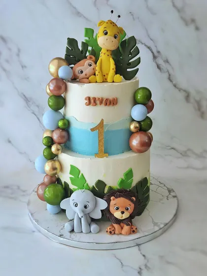 A two-tier jungle cake for Jevon's first birthday. This butterscotch cake is decorated with a balloon-style garland and cute, hand-sculpted fondant animals.