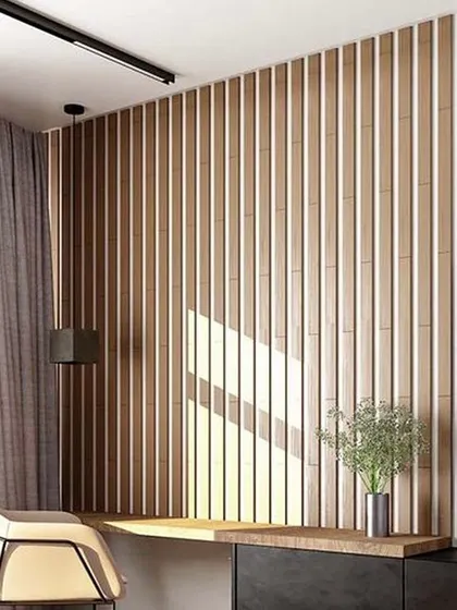 A study or reading nook integrated into a living space. The fluted wood paneling serves as a textured backdrop for a simple, wall-mounted desk, creating a functional workspace without compromising the room's aesthetic.