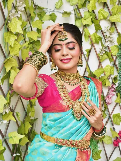 A festive look perfect for any celebration. This model is wearing a beautiful antique gold set with green stone accents, ideal for a wedding guest or bridesmaid.