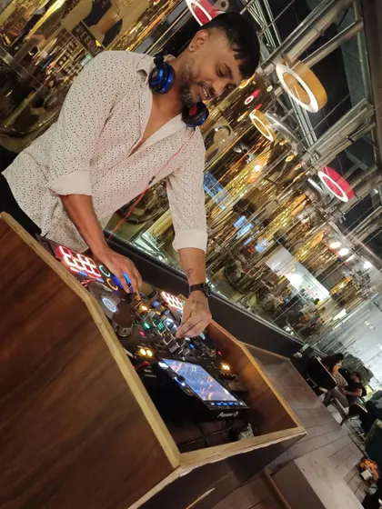 A different perspective of me at the DJ console. You can see the intricate setup and the focus required to manage the music and the crowd's experience.