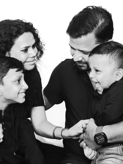 A candid family moment captured in the studio. Using a black and white format helps focus on the pure joy and interaction between parents and their children, creating a timeless memory.