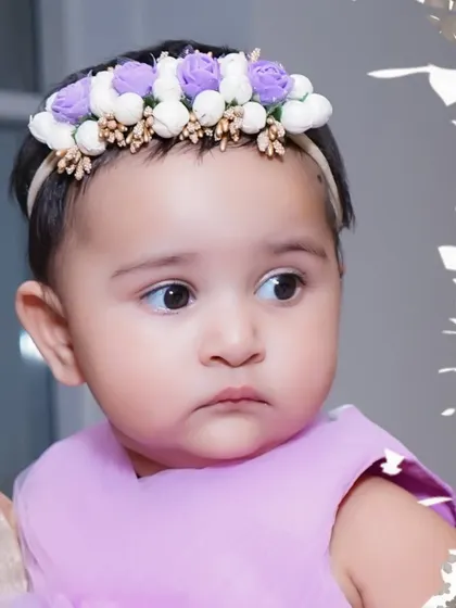 A beautiful close-up portrait of a baby girl wearing a delicate floral headband, showcasing the sharp detail we capture in our photos.