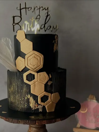This two-tiered black and gold cake has a modern, geometric design. I used a wood grain texture on the bottom tier and added gold hexagonal accents for a sophisticated and bold look.