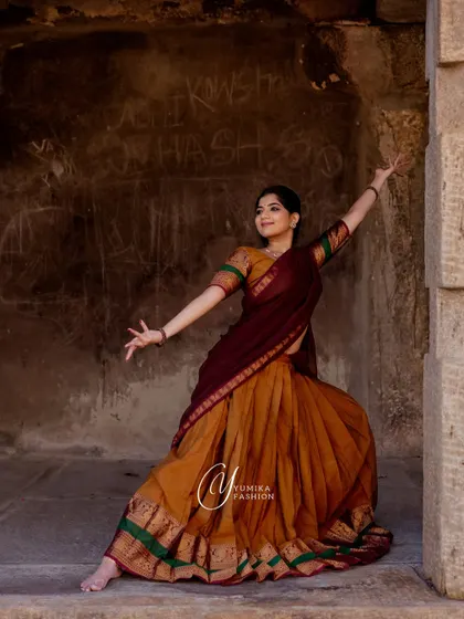 Posing within the magnificent architecture of a South Indian temple. The grandeur of the stone pillars and the open sky creates a breathtaking canvas for a dance portrait.
