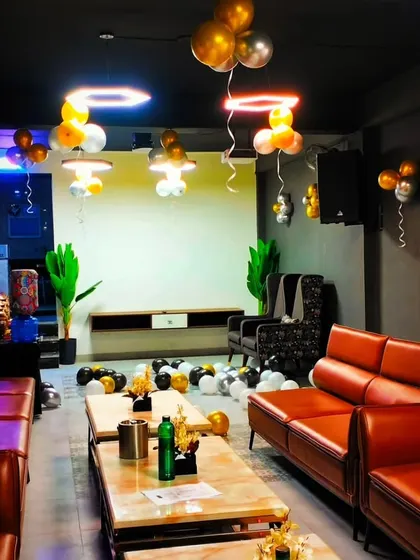 A party setup in a private room with gold, black, and white balloons. The balloons on the ceiling and floor create a fun and celebratory atmosphere.