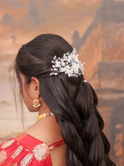 A closer view of this elegant bridal hairstyle. The delicate, crystal-like hair accessory adds a touch of modern sparkle to the classic braided look.