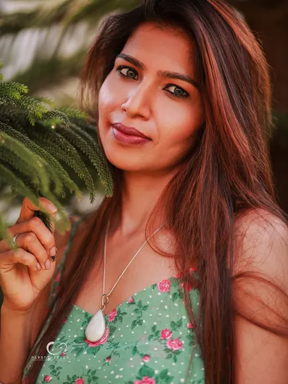 A calm and confident close-up. The natural framing of the leaves adds depth and texture to this beautiful outdoor portrait.
