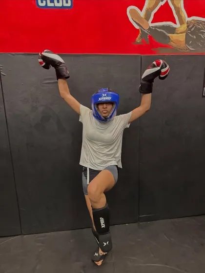 A female fighter in full gear, celebrating her power. Every punch, every kick, every drop of sweat makes you stronger and more fierce.