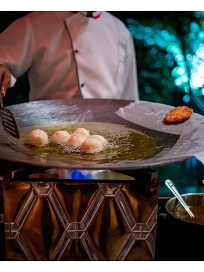 A chef deep-frying savoury items in a large kadai, a classic live station for preparing traditional Indian snacks.