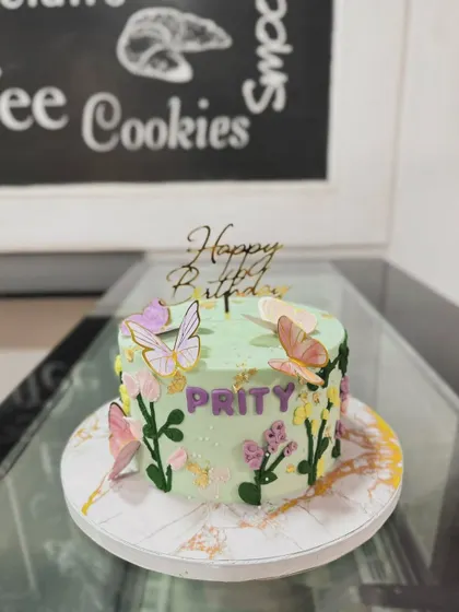 A garden-themed cake with butterflies and piped flowers, personalized for Prity.