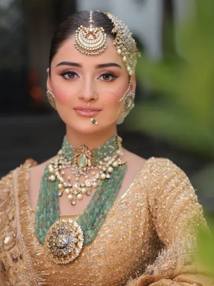 A direct, confident gaze from a bride in her full glory. The styling focuses on balancing the heavy jewelry with a clean makeup look to let her natural beauty shine through.