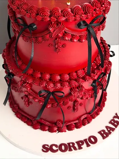 A detailed shot of the bottom tier of the red Scorpio cake, showing the intricate piping and the personalized message.