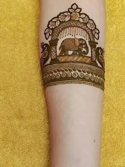 A simple yet elegant armband design featuring a decorated elephant inside a royal arch, flanked by two peacocks.