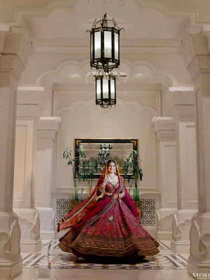 A beautiful full-length portrait of the bride, Kritika, twirling in her lehenga in a grand hotel corridor.