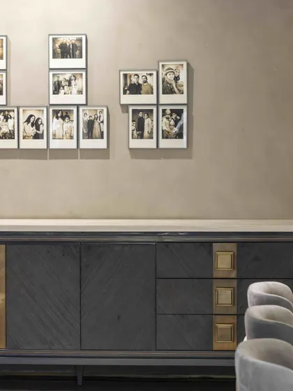 A close-up of the custom sideboard in the family lounge, featuring a unique mix of materials and finishes. Above it, the collection of family photos adds a deeply personal touch to the design.