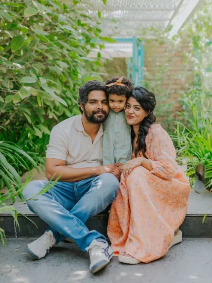 A family sits together on the steps in a garden, surrounded by greenery. Their relaxed and happy expressions make this a perfect outdoor family portrait.