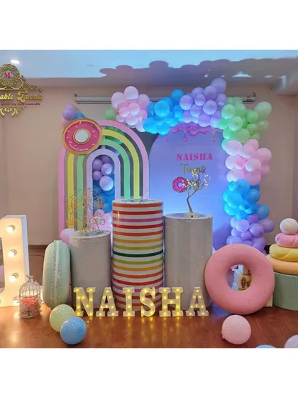 A full view of a 'Candyland' themed first birthday setup, featuring donut and cupcake props, rainbow backdrops, and marquee letters.