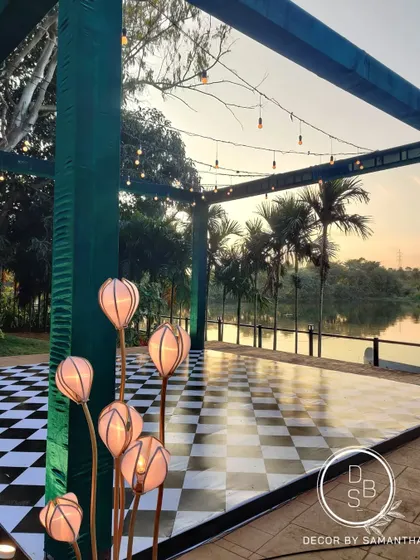 The checkered dance floor set by the lake, ready for the evening's celebrations. The custom floral-shaped lights add a whimsical touch to the space.