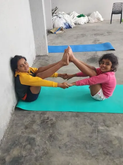 Using the wall for support, these young campers successfully hold a partner boat pose.
